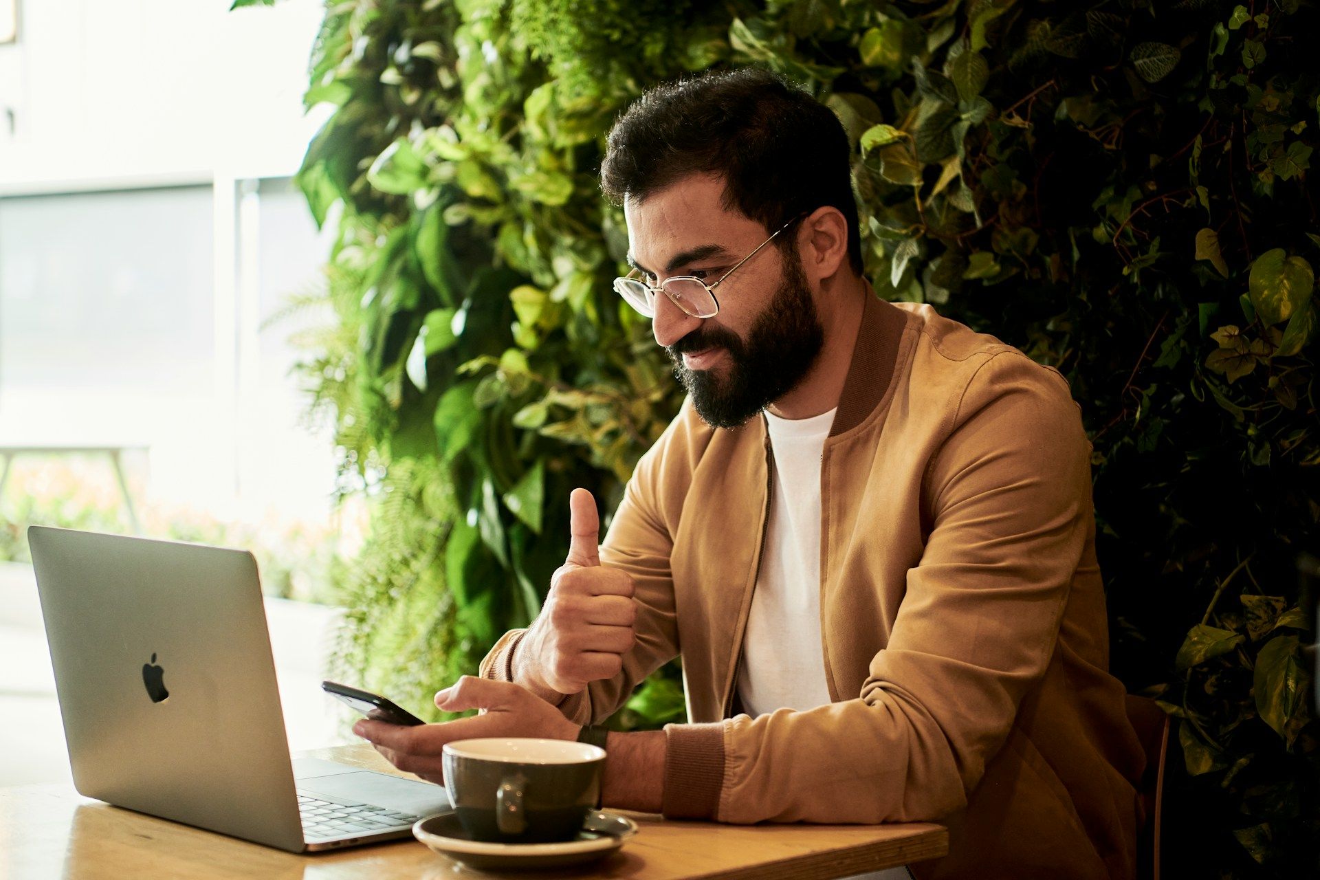 Photo of a man in front of a laptop smiling and giving a thumbs up