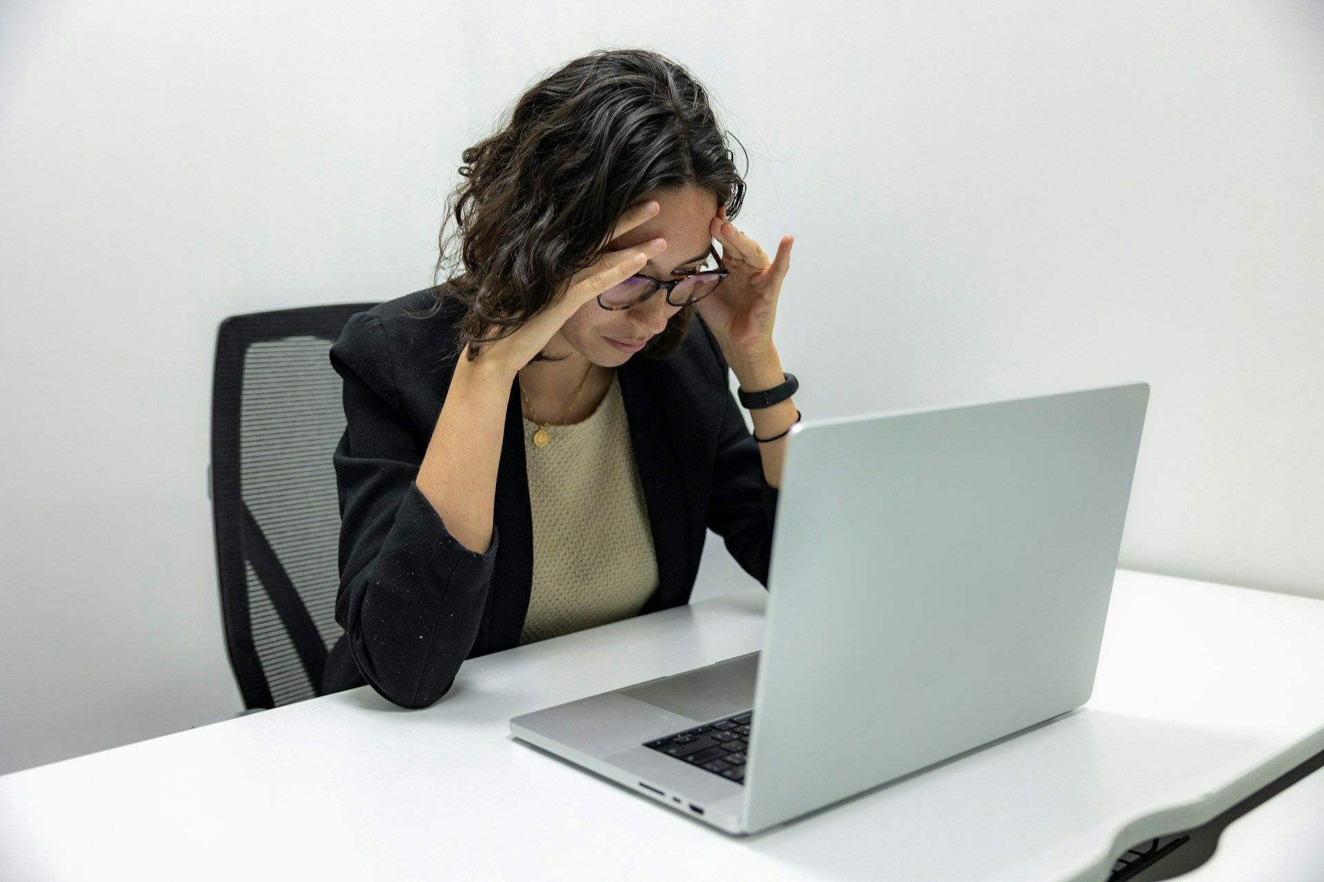Photo of a woman sitting in front of a laptop looking concerned